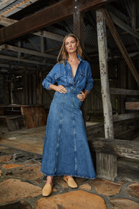 A model wearing a long denim dress, confidently showcasing the champagne Aspen slippers in an Autumn/Winter 2024 campaign picture.