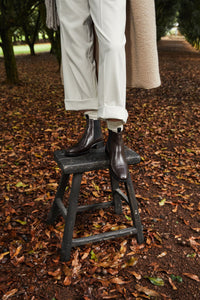 styled photo with model in wearing 'oak book', standing on a stool amongst trees