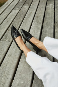 Close Up Shoes: Model showcasing The Poplar Pointed Flat in Black Leather with Tassels, demonstrating its versatility and fashionable style.