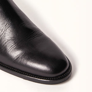 Single 3/4 Toe close up of Birch Boot in Black, highlighting the sleek leather material and equestrian-inspired design