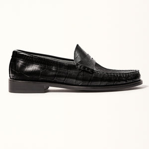 Single side view of Penny Loafer in Black Croc, highlighting the smooth leather inner and sole, and the elegant silhouette of the loafer.
