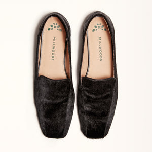 A pair of black ballet flats with a square toe design made of pony hair material, shown from the front in a double view.